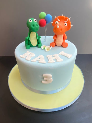 2 dinosaurs on a single tier birthday cake with balloons