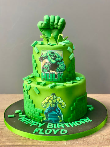 Green two tiered cake with hulk decorations and fist on top