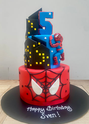 Spider-Man themed birthday cake with number 5 and cityscape design on a blue and red background
