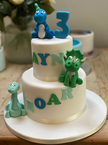 2 tier birthday cake with blue and green dinosaurs and ROAR written across the front