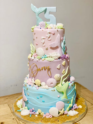 3 tier pastel coloured mermaid cake with lots of sea shells and under the sea decorations