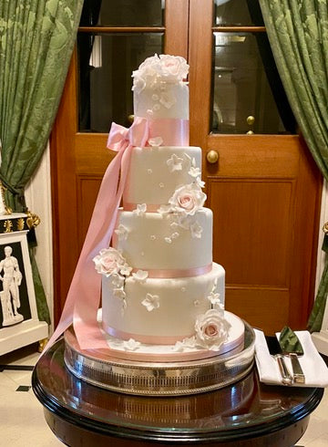 Elegant Four-tiered wedding cake with pink ribbons, roses and flowers
