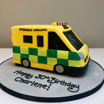Cake shaped like an ambulance with 'Emergency Ambulance' text, checkered pattern,