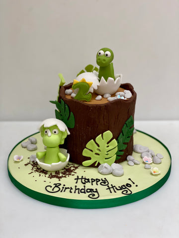 Tree shaped cake with baby dinosaurs hatching out of eggs on it
