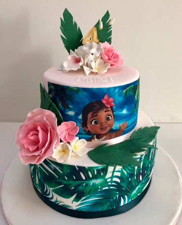 2 tiered birthday cake with baby moana and tropical leaves and flowers