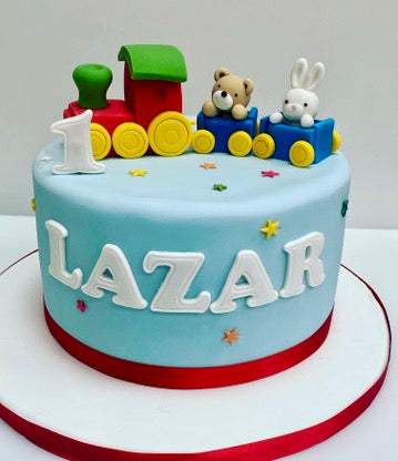 Child's birthday cake with a colourful train and a teddy and bunny in the carriage