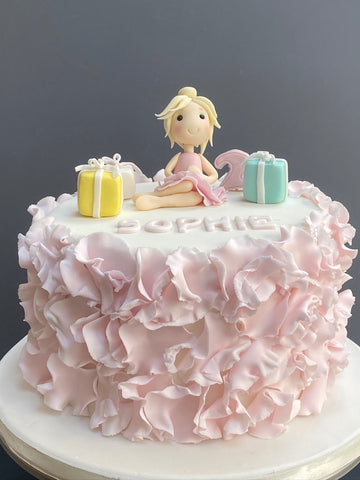 Ballet princess on a frilled cake with gifts around her
