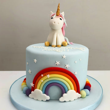 single tier pale blue birthday cake with rainbow, unicorn and rainbow balls