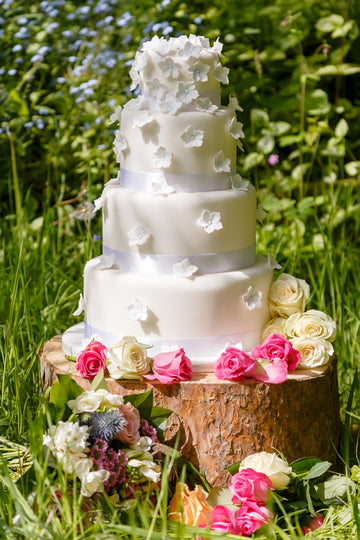 white wedding cake with tumbling blue hydrangea blossoms falling down the cake delivered to london