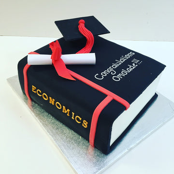 Graduation-themed cake with economics book, mortarboard, and diploma