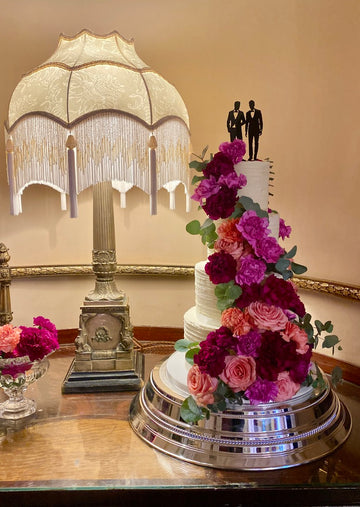 Buttercream 4 Tiered Wedding with Bright pink, red and orange fresh flower cascade down the front and a gay men topper
