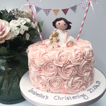 Christening cake with buttercream roses and a little girl with bunting on top