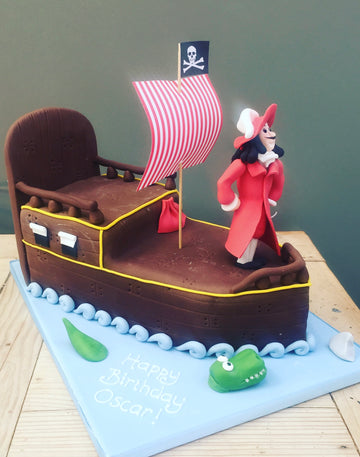 Birthday cake in the shape of a pirate ship with Captain Hook from Peter Pan on it