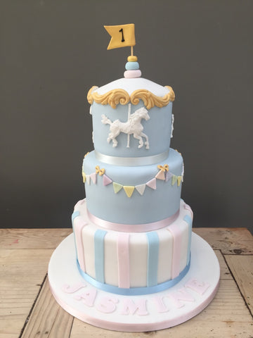 Three-tiered birthday cake with carousel design in pastel colours