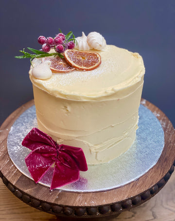Buttercream christmas cake with candied oranges, berries and a burgundy bow