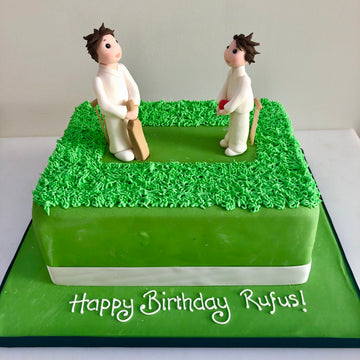 Cake with two figures on top playing cricket