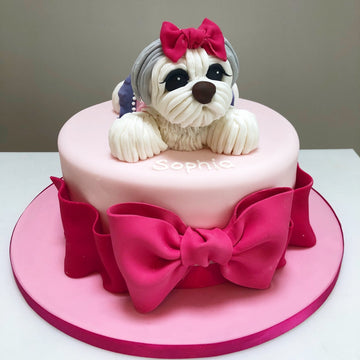 Birthday cake decorated with a pet dog and a big pink bow