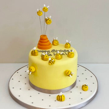 Birthday cake decorated with bees and a honey pot