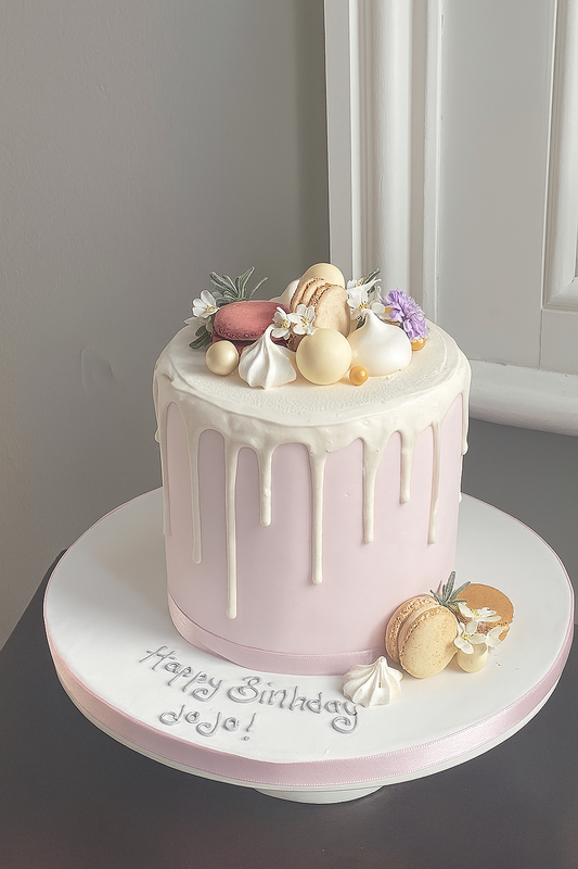 Pink drip cake with macarons, meringue kisses and chocolates to decorate