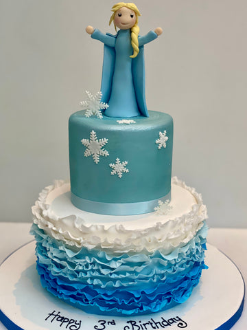 Cake decorated with an ombre frill and a figure of Elsa from Frozen on top