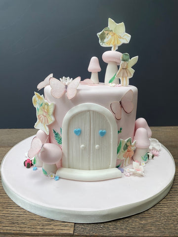 Cake decorated with a fairy door, toadstools and butterflies