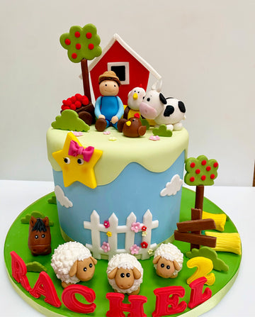 Tall birthday cake decorated in farm theme with barn, farmer and farm animals