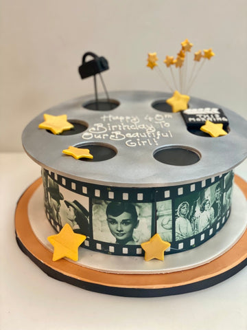 Cake designed like a movie reel with film strip and star decorations on a white background