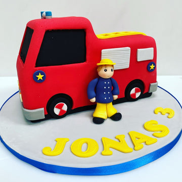 Fire engine shaped birthday cake with sugar fireman sam next to it
