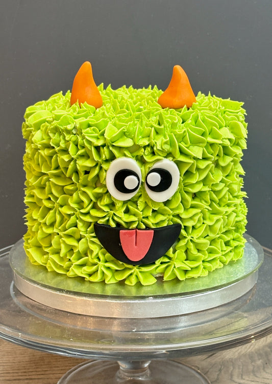 halloween cake styled to look like a green monster wtih horns and goggly eyes. Perfect halloween cake for a halloween party