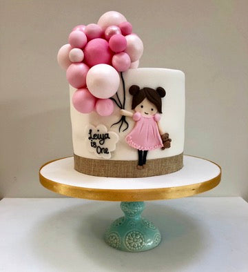 Birthday Cake with balloons and a figurine of a girl on a white background