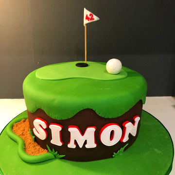 Golf-themed birthday cake with 'SIMON' on a green background