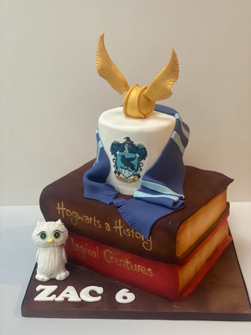 Stack of cakes carved to look like harry potter books with and owl and snitch to decorate