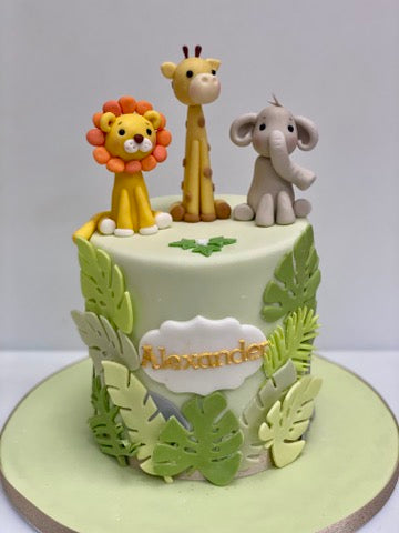 birthday cake covered with jungle leaves and lion, giraffe and elephant