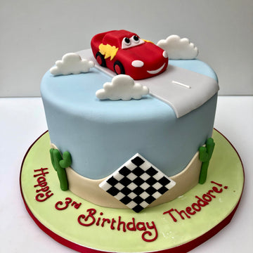 Birthday cake with lightening mcqueen on top and chequered flags