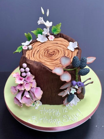 Birthday cake decorated to look like a log with wild flowers and berries to decorate made from sugar