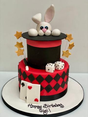 2 Tiered Birthday cake decorated to look like a magicians hat, with rabbit, playing cards and dice