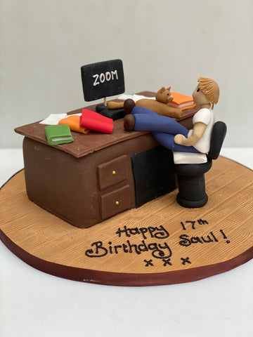 Cake carved to look like a desk with a man sat working at his computer