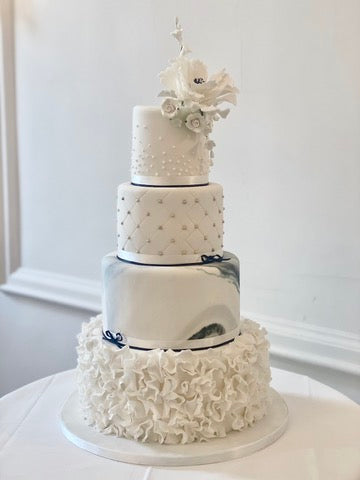 4 Tier White Wedding Cake with Marble tier, Ruffle tier and Quilted tier and piped champagne bubble tier finished with white sugar flowers