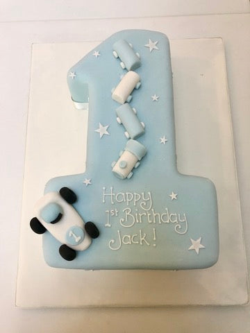 Blue birthday cake shaped like the number one with small cars and toy train