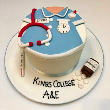 Cake designed to resemble a nurse's medical uniform with stethoscope, clock, and pill bottle on a white background