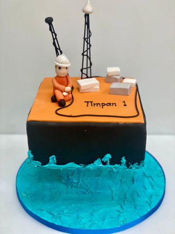 Cake designed to resemble a drilling platform oil rig with a figure labeled 'Timpan 1' on a blue base.
