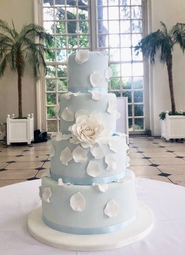 Pale Blue 4 tier wedding cake with large white rose and falling rose petals delivered to kew gardens in london