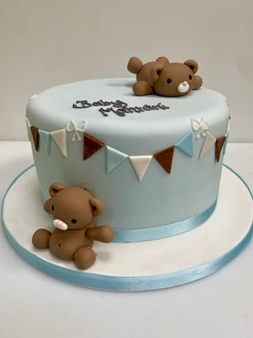 Birthday or christening or babyshower cake with teddies playing to decorate and bunting around the sides of the cake