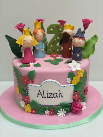 pink birthday cake decorated with figures of ben and holly, the king and queen and lots of flowers