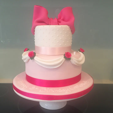 2 tiered cake with pink bows, roses and drapes or swags