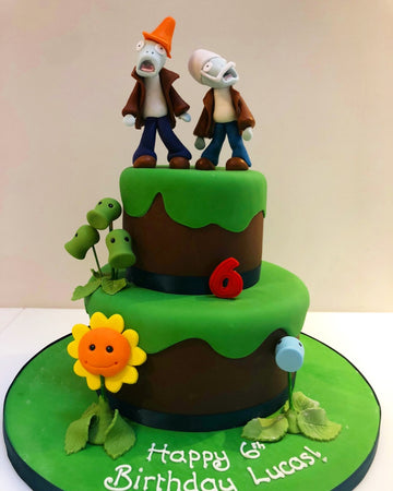 Two tier birthday cake with figures from plants and zombies to decorate