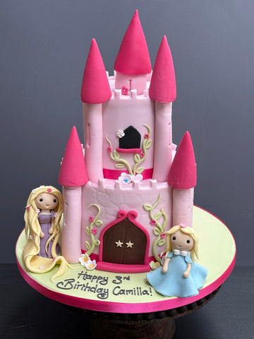 Pink Castle shaped birthday cake with rapunzel and a little girl princess next to it