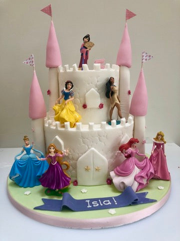 Castle two tiered cake with disney princess figurines on it