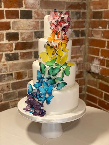 4 tiered wedding cake decorated with a swathe of rainbow butterflies