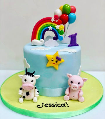 Birthday cake decorated with a rainbow, balloons, cow and pig and star